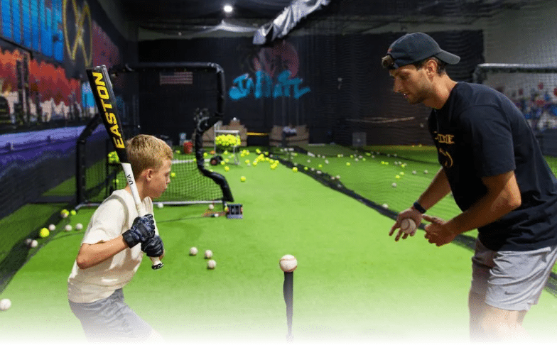 Infinite Hitting coach showing a young boy how to hit a baseball off of a tee